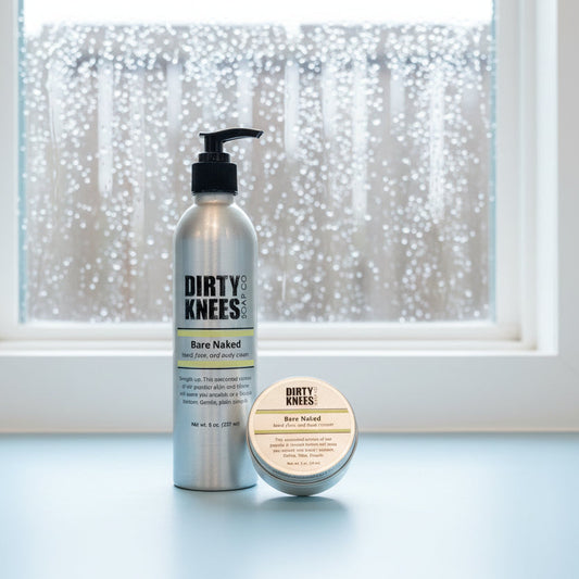 Two bottles of 'Dirty Knees' hair product on a white surface with a wooden floor in the background.